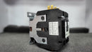 A close-up photo of a black Eaton CONTACTOR, model C25FNF360, shows its white specification label, metal mounting bracket, and gold terminals. The 60 amp device is placed on gray foam with a blurred background.